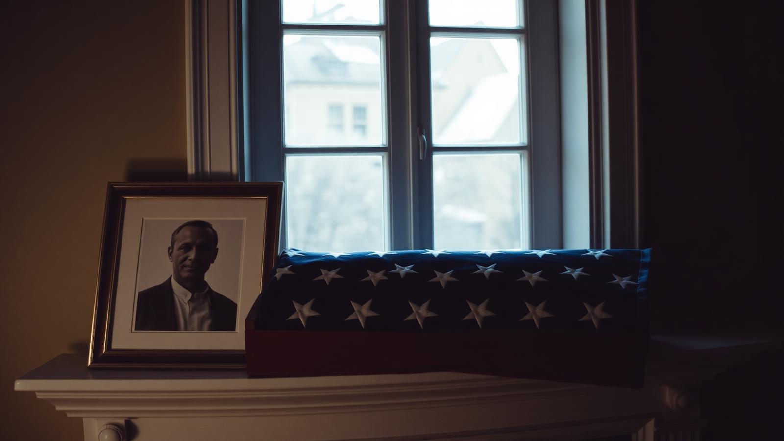 Folded American flag in a display case on a mantelpiece, with soft window light.